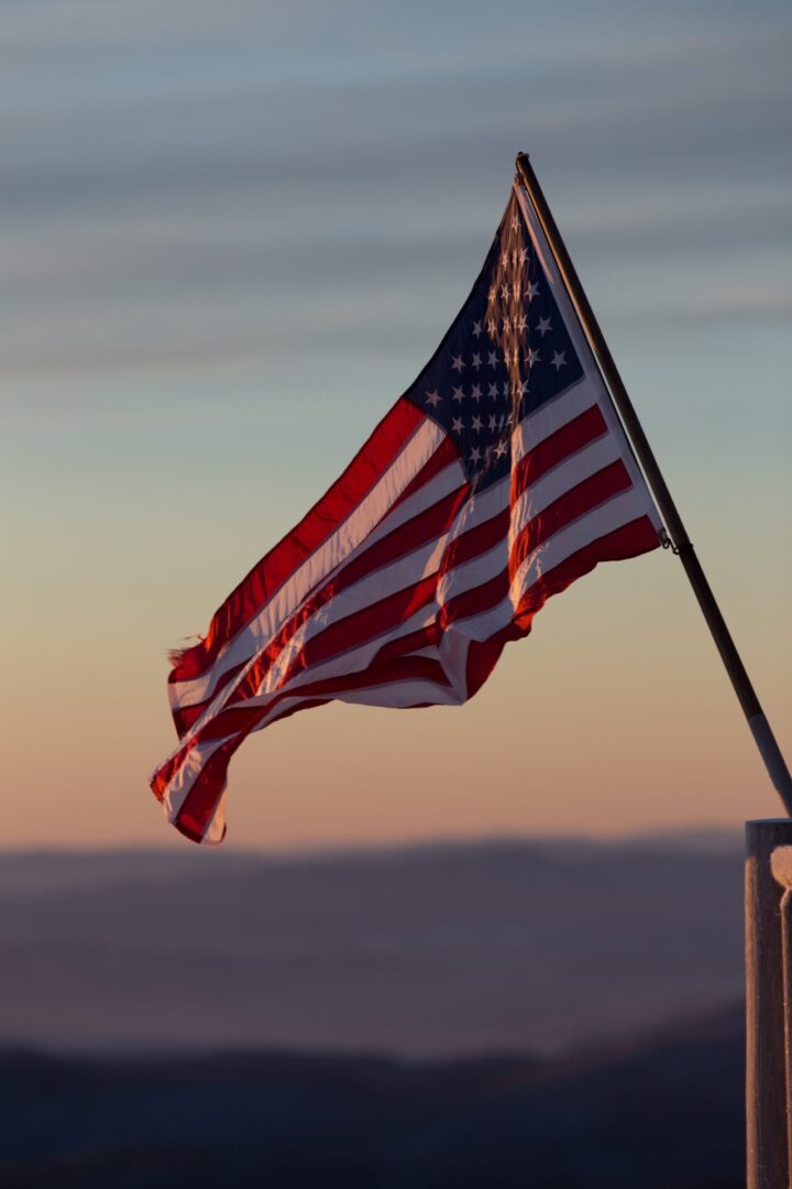 A flag flying in the wind on top of a hill.